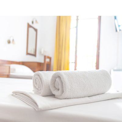 Two white towels are on the bed in hotel room. Close-up horizontal background. Space for text.